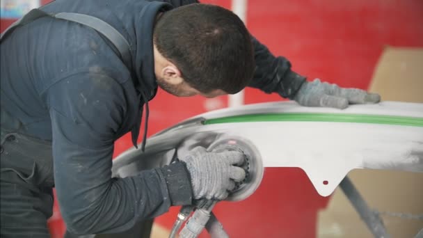 Man worker in uniform polishing car bumper in a service station — Stock Video