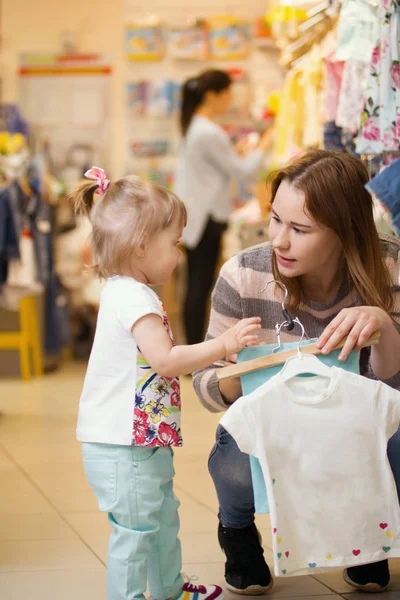 Fiatal nő a lányával, kiválasztja ruhákat — Stock Fotó