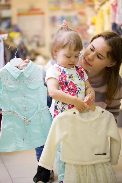 Atractiva madre con hija eligiendo vestidos — Foto de Stock