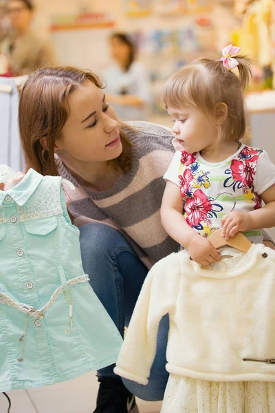 Joven madre con hija en la tienda de ropa para niños — Foto de Stock