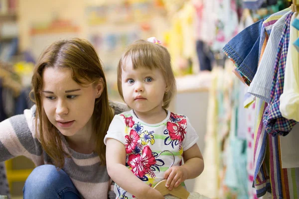 Fiatal kaukázusi anya és lánya az a gyermek ruha bolt — Stock Fotó