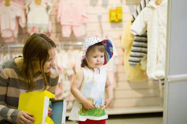 Joven madre y su hija en el sombrero en la tienda de niños — Foto de Stock