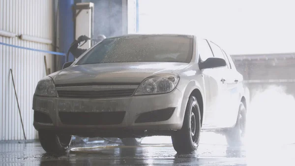 Arbeiter reinigt Auto mit Wasserschlauch — Stockfoto