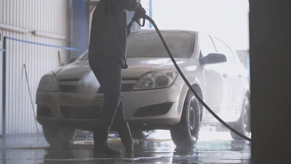 Pracownik z węża w zakładzie mycie samochodu — Zdjęcie stockowe
