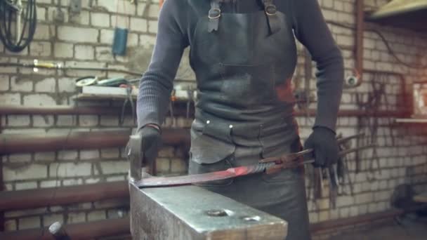 Кузнец в защитных очках работает в мастерской — стоковое видео
