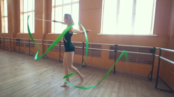 Gimnasia - mujer joven bailando con una cinta verde-entrenamiento de un ejercicio de gimnasia, cámara lenta — Vídeo de stock
