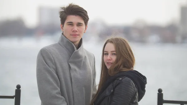 Молодий чоловік обіймає свою дівчину на фоні на березі річки — стокове фото