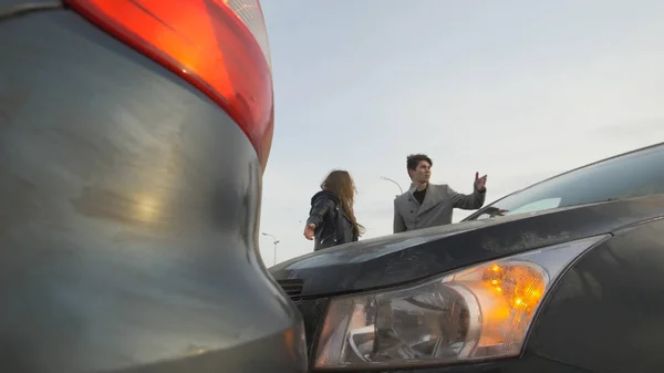 Молодой человек и женщина спорят из-за автомобильной аварии — стоковое фото