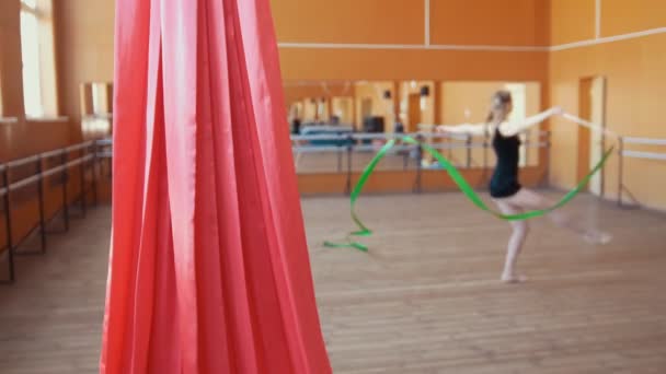 Rote Seide vor einer jungen Frau, die eine Gymnastikübung mit Schleife trainiert — Stockvideo