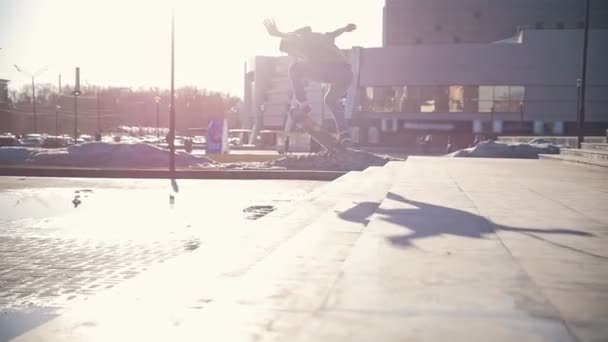 Чоловік скейтбордист стрибає вниз по сходах на відкритому повітрі в сонячний день — стокове відео