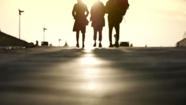 Трое друзей идут по улице на закате — стоковое видео