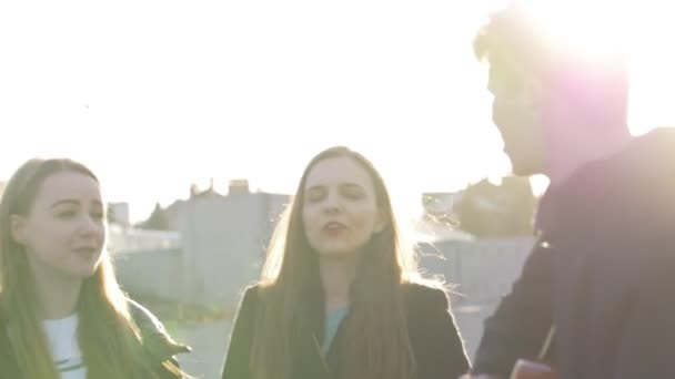 Trzech przyjaciół, śpiewając z gitarą i zabawy o zachodzie słońca — Wideo stockowe