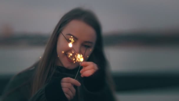 日没を屋外で線香花火を楽しんで若い白人女性 — ストック動画
