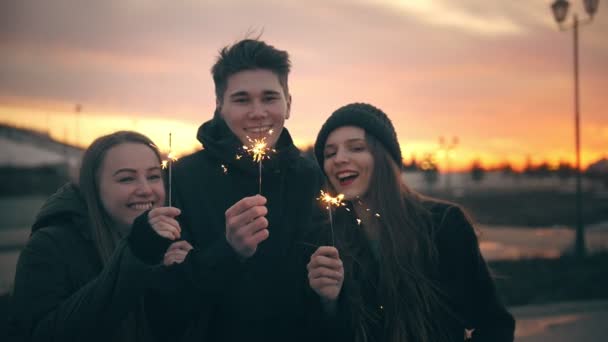 Três amigos se divertindo com sparkler ao pôr do sol ao ar livre — Vídeo de Stock