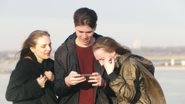 Grupo de amigos mirando por teléfono y riendo cerca del muelle — Vídeos de Stock