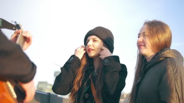 Atractivas novias cantando con un chico tocando la guitarra al atardecer — Vídeo de stock