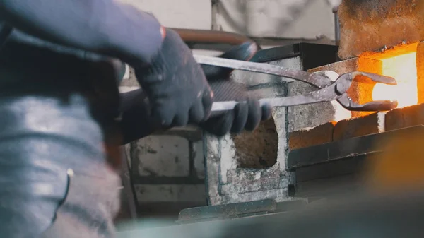 Кузнец-ремесленник работает со сталью в кузнице — стоковое фото