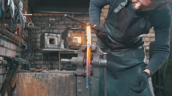 Кузнец формирует горячую сталь с молотком в кузнице — стоковое фото