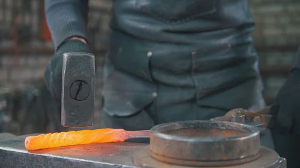 Der Schmied gibt einem glühenden Metallgegenstand mit einem Hammer Form — Stockfoto