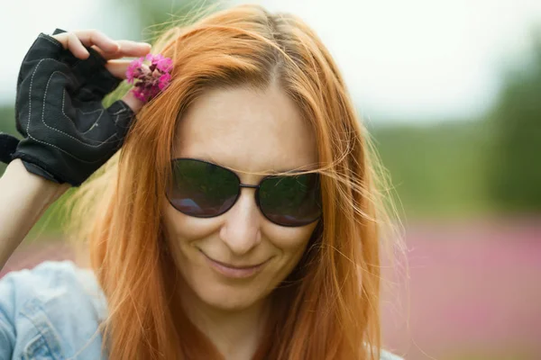 Портрет красивой молодой женщины в очках с цветами в волосах на улице — стоковое фото