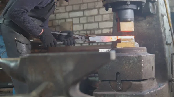 Ferreiro forjando ferro quente vermelho na bigorna - martelo automático — Fotografia de Stock