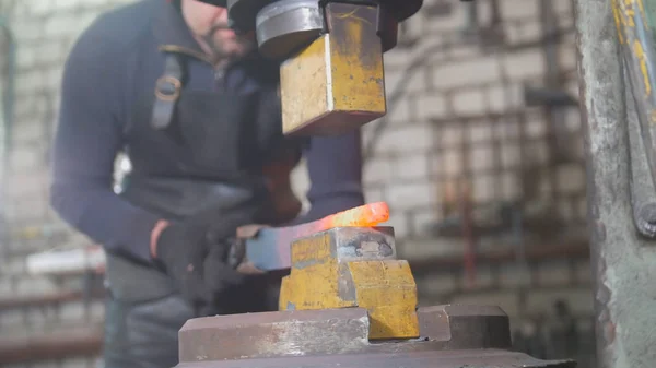 Automatic hammering - blacksmith forging red hot iron on anvil, extreme close-up