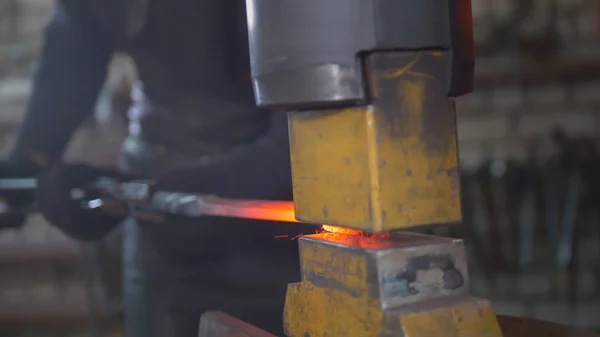 O metal fundido é processado sob pressão nas mãos de um ferreiro — Fotografia de Stock