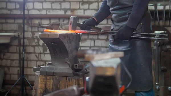 Herrero hombre musculoso con martillo en forja creando cuchillo de acero — Foto de Stock