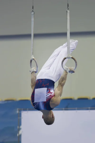 Şampiyona jimnastikci Yüzükler üzerinde baş aşağı genç atletik adam — Stok fotoğraf