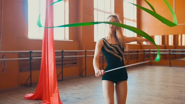 Ritmische gymnastiek - jonge vrouw een gymnastiek opleiding oefening met een groen lint — Stockfoto