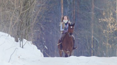 Genç kadın binici orman donmuş kışın sürüklenir üzerinden bir siyah at binme