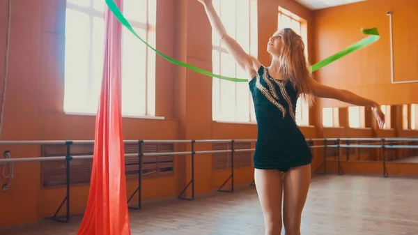Ритмічна гімнастика - молода жінка тренує гімнастику вправами з зеленою стрічкою — стокове фото