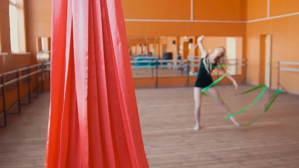 Червоний шовк перед молодою жінкою тренує гімнастику стрічкою - дефокусований — стокове фото