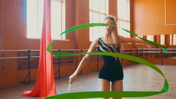 Художественная гимнастика - молодая женщина тренирует гимнастику с зеленой лентой — стоковое фото
