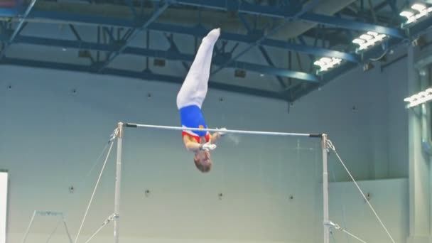 Καζάν, Ρωσία - Απριλίου 18, 2018: All-Ρωσίας γυμναστική πρωτάθλημα - μυώδης άνδρας αθλητής εκτελεί ένα άλμα πάνω από το μπαρ — Αρχείο Βίντεο