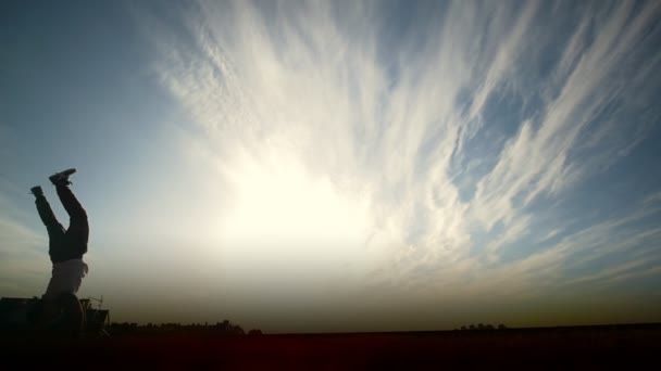 Jovem realizando salto mortal na frente do sol, câmera lenta — Vídeo de Stock