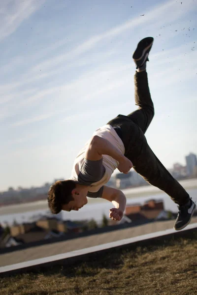 Giovane sportivo acrobatico maschile esegue trucchi salta davanti allo skyline — Foto Stock