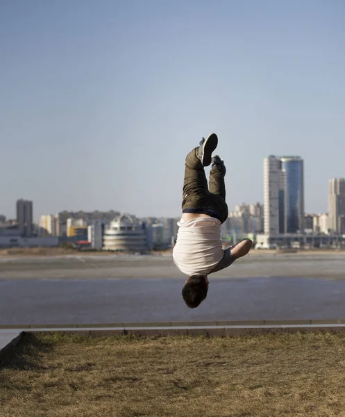 Молодий чоловічий акробатичний спортсмен виконує трюки догори ногами перед горизонтом — стокове фото