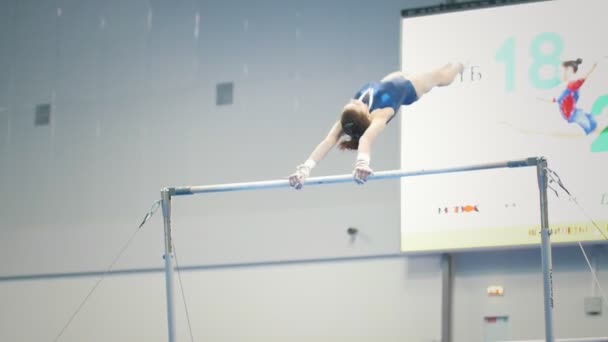 KAZAN, RUSSIA - APRIL 18, 2018: All-Russian gymnastics championship - young woman gymnast hanging on uneven bars at the championship — Stock Video