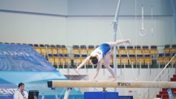 KAZAN, RUSIA - 18 DE ABRIL DE 2018: Campeonato de Gimnasia de toda Rusia - chica atleta gimnasta realiza trucos acrobticos en la viga de equilibrio, cámara lenta — Vídeos de Stock