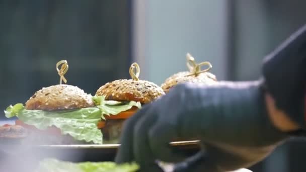 Handen van chef op commerciële keuken serveert hamburgers op de plaat - binnen het restaurant — Stockvideo