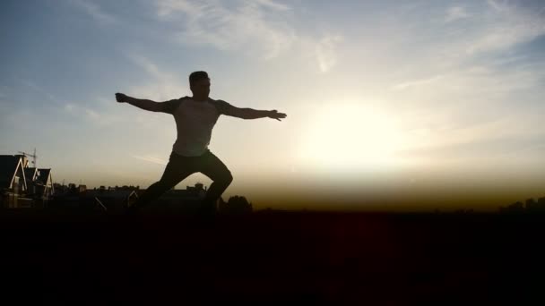 Young man performing somersault in front of the sun, slow-motion — Stock Video