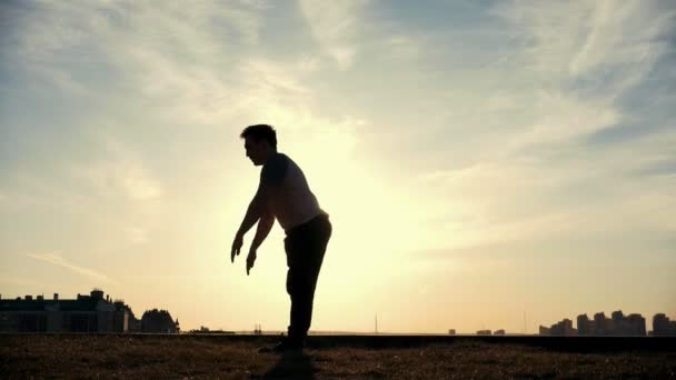 Медленное движение - молодой самец Parkour обманщик выполняет удивительные сальто перед солнцем — стоковое видео