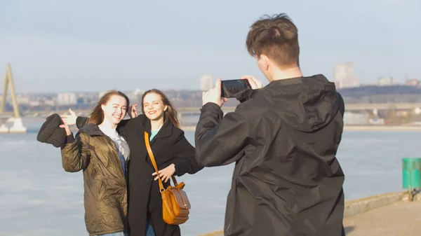 Хлопець бере фотографію для двох привабливі подруг на набережній у сонячний день — стокове фото