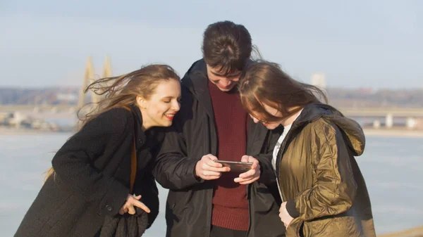 Jóvenes amigos viendo fotos y riendo en el muelle —  Fotos de Stock