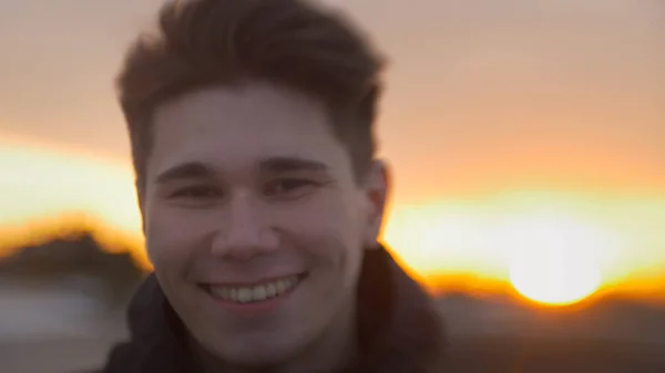 Портрет молодого привабливого чоловіка, який посміхається на заході сонця — стокове фото