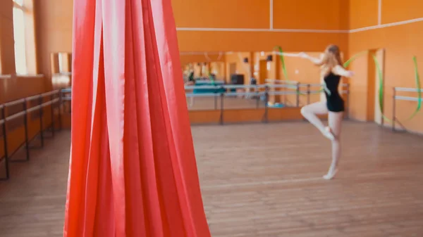 Soie rouge devant une jeune femme entraînant un exercice de gymnastique avec un ruban — Photo