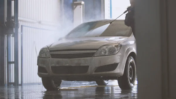 Woman worker with the water hose in car-washing facility — Stock Photo, Image