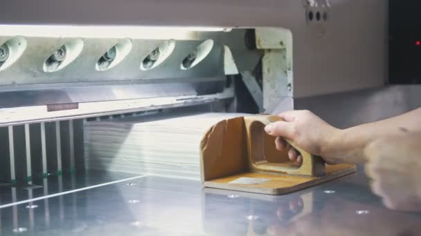 Handen van werknemer wegneemt riemen van papier uit snijden maschine — Stockvideo