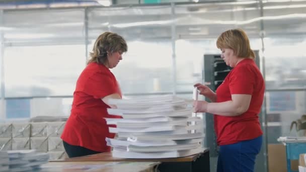 Trabajadoras clasificando una pila de papel en la tipografía — Vídeos de Stock